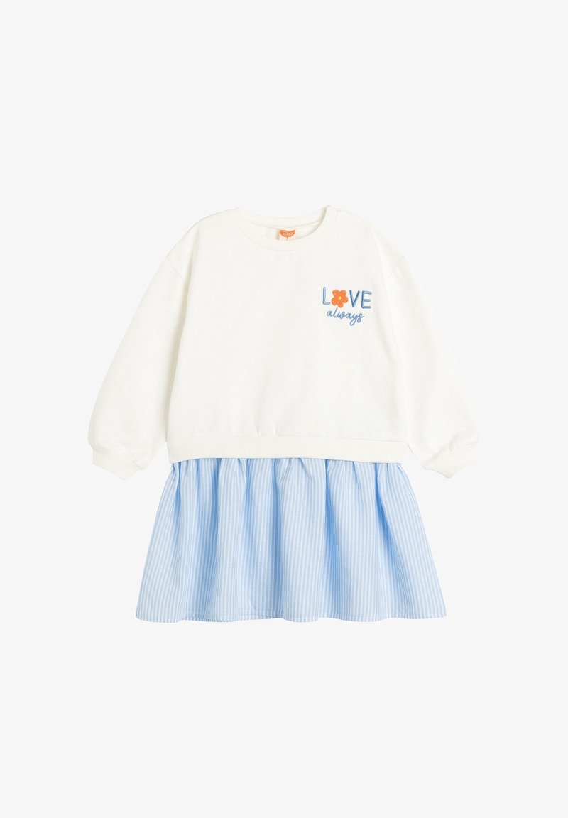 Haut blanc à manches longues avec le texte « LOVE always » et une fleur orange au-dessus d'une jupe froncée rayée verticalement bleu et blanc.