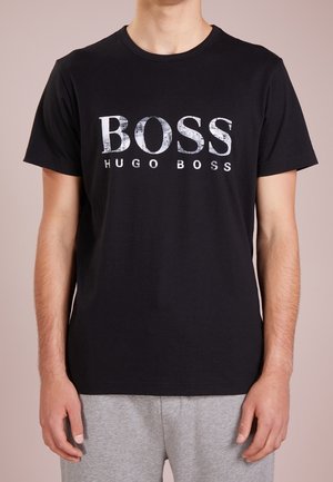 Zwart katoenen T-shirt met een ronde hals en korte mouwen. Voorzien van een groot wit "BOSS" logo met een verweerd effect, vergezeld van de tekst "HUGO BOSS".