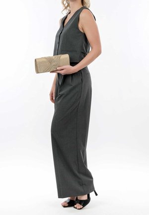 Grijs broekpak met een aangesloten vest, aangevuld met een goudkleurige, getextureerde clutch en zwarte open-toe hakken. Eenvoudig design met minimale details.