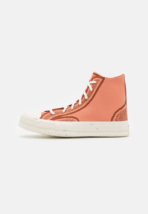 High-Top-Casual-Sneaker aus pfirsichfarbenem Strickstoff mit rostfarbenen Umrissen und weißen Schnürsenkeln auf einer weißen Gummisohle.