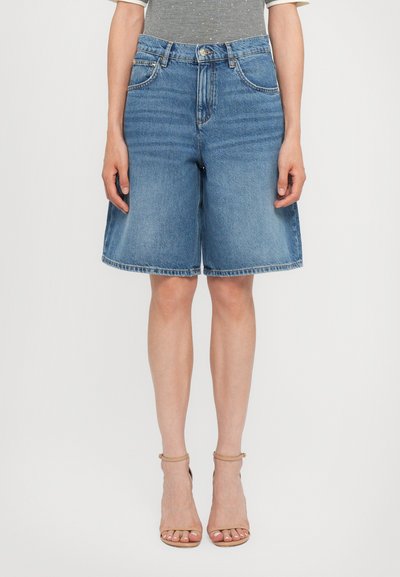 Blue denim shorts with a straight leg fit, mid-rise waist, and frayed hem, paired with light beige strappy high-heeled sandals.
