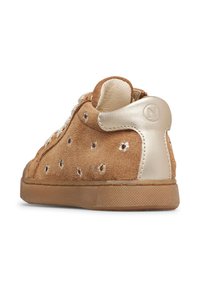 Zapatilla de ante marrón con pestaña del talón en dorado metálico, detalles perforados en los laterales y suela de goma texturizada, vista desde un ángulo trasero.