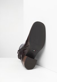 Bottines en cuir marron avec fermeture éclaire sur le côté, bout arrondi et semelle en caoutchouc texturée avec un petit talon. Fabriquées en Italie.