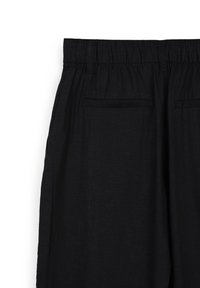 Pantaloni neri in lino con vita elastica, due tasche laterali e una texture liscia. Il tessuto ha un aspetto leggermente stropicciato.