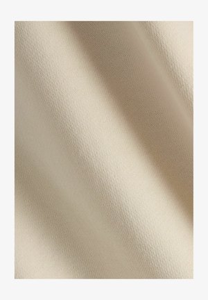Beige textilmaterial med en slät, strukturerad yta och ett subtilt vävmönster som visar ett mjukt, ljust utseende.