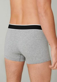 Gray cotton boxer shorts with a fitted design, featuring a black waistband with a white accent stripe, showcasing a smooth texture.