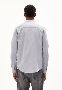 Lichtblauw langetermijn shirt gemaakt van geweven stof, met een standaardkraag en knopenmanchetten, een licht gebogen zoom en rugpas.