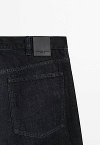 Tummansiniset farkut, joissa teksturoitu kangas, takatasku, suora leikkaus ja musta nahkalogo, jossa lukee "MASSIMO DUTTI".