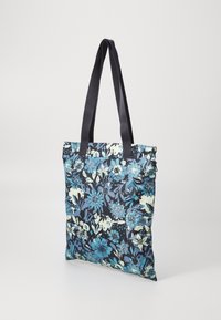 Floral tote bag made of fabric, featuring a navy background with blue and light green floral patterns. Two sturdy black handles.