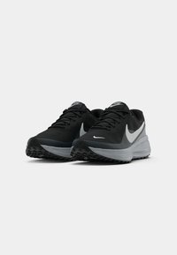Scarpe da atletica nere con tomaia strutturata, dotate di una suola grigia e logo swoosh bianco, progettate per comfort e aderenza.
