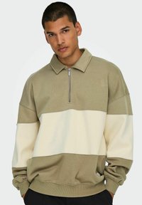Khaki and cream quarter-zip sweatshirt with a fold-down collar, features a color-block design and ribbed cuffs and hem. Soft texture.