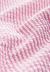 Baumwollstoff in Rosa mit weißen Streifen. Die Textur wirkt weich und leicht strukturiert und zeigt ein durchgängiges Muster.