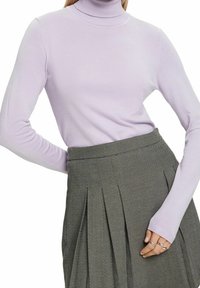 Hellblau-lila Rollkragenpullover aus einem weichen Strickstoff mit langen Ärmeln. Kombiniert mit einem grauen gemusterten Rock mit Falten.