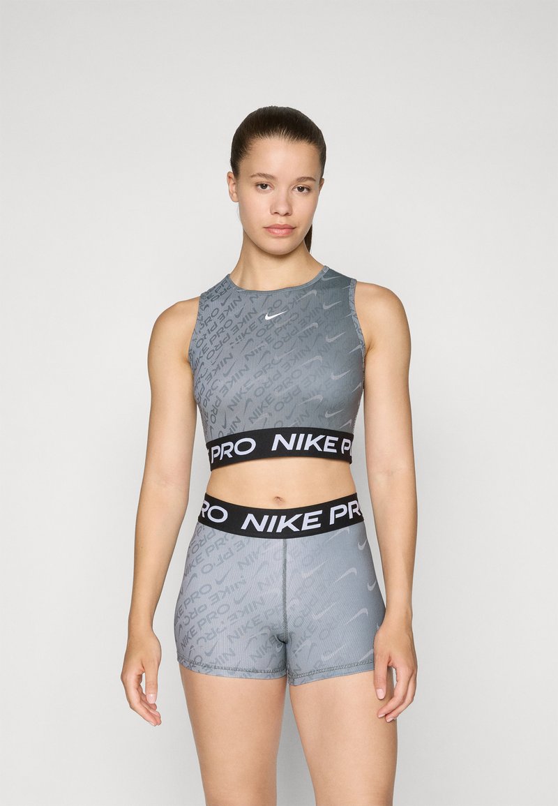 Šedá športová súprava z crop topu a šortiek, ktorá má ryhovanú textúru, abstraktné vzory a čierny pružný pás Nike Pro s logom.