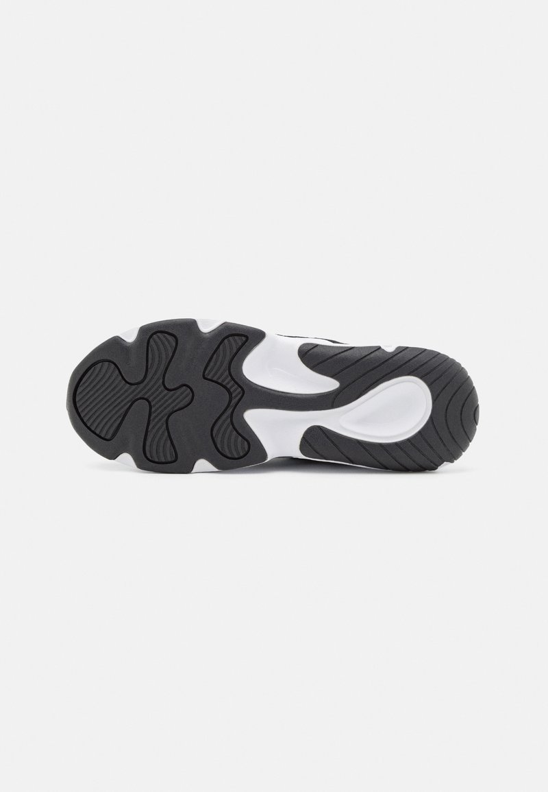 Semelle de sneaker en noir et blanc avec une surface en caoutchouc texturé, présentant un motif en vagues et des rainures flexibles pour une meilleure adhérence.