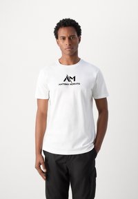 T-shirt blanc à manches courtes en coton, avec un logo noir affichant "ANTONY MORATO" de manière bien visible sur la poitrine. Design minimaliste.