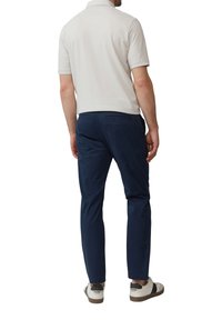 Polo shirt gris clair à manches courtes, associé à un pantalon slim-fit bleu marine et des baskets blanches avec des accents noirs.