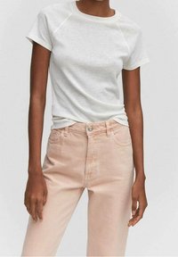 T-shirt blanc à manches courtes avec un col rond, associé à un jean taille haute rose clair avec poches avant et fermeture par bouton.