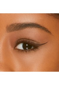 Close-up van een oog met een gedefinieerde winged eyeliner, bruine oogschaduw en dikke wimpers. De huidtint is warm met een gladde textuur.