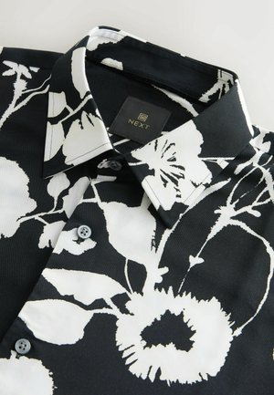 Schwarzes Hemd mit einem floralen Muster in Weiß. Hergestellt aus glattem Stoff, verfügt es über einen spitzen Kragen und eine Knopfverschluss mit grauen Knöpfen.