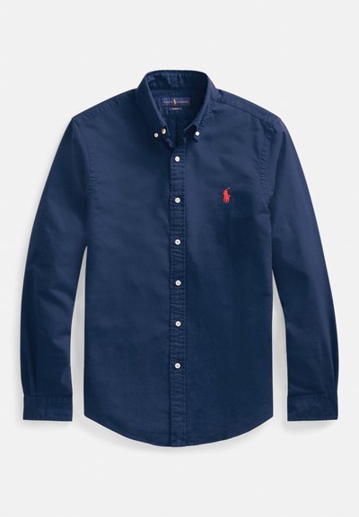 Navy blue button-down shirt made of cotton, featuring a pointed collar, long sleeves, and a small red embroidered logo on the chest.