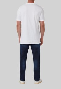 Witte t-shirt met korte mouwen, gemaakt van katoen, gecombineerd met donkerblauwe denim jeans met een rechte pijl en witte sneakers.