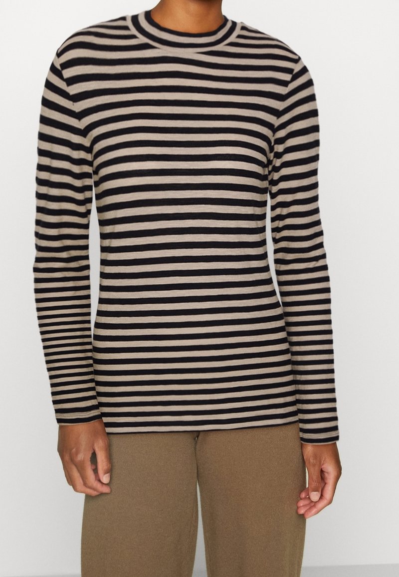 Stribet langærmet top i beige og sort. Rund halsudskæring, figursyet design, glat tekstur. Kombineret med løse beige bukser.