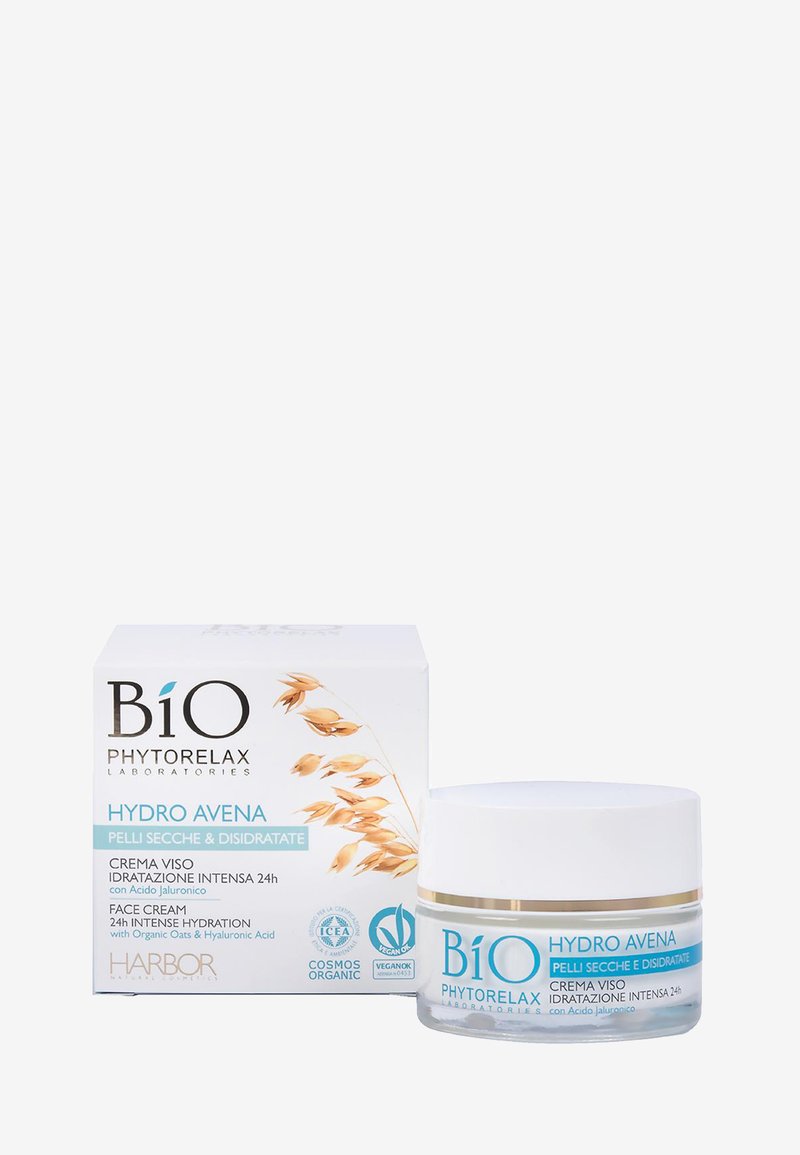 Crème pour le visage BiO Hydro Avena dans un pot transparent avec un couvercle blanc. L'emballage présente une boîte blanche avec des accents dorés et des illustrations d'avoine.