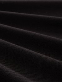 Primer plano de una tela negra acanalada con suaves pliegues y textura de punto visible en poca luz.
