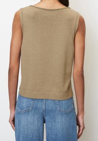 Sleeveless beige knit top worn by person facing away, paired with high-waisted blue denim jeans with back pockets.