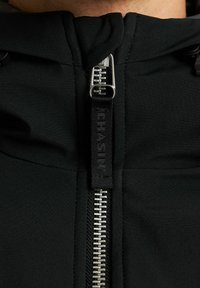 Sudadera negra con cremallera frontal de metal, la textura de la tela es suave, cuenta con capucha y marca en el tirador de la cremallera.