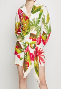 Kurzärmliges Kleid aus leichtem Stoff, mit einem weißen Grundton und lebhaften roten und grünen Blattmustern, einem gebundenen Taillengürtel und einem Fransen-Saum.