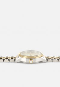 Silberne und goldene Edelstahl-Uhr mit einem runden Ziffernblatt, goldener Lünette und cremefarbenem Ziffernblatt. Verfügt über eine Krone mit einem weißen Akzent und einem Gliederband.