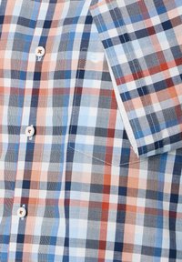 Kurzarm-Hemd aus kariertem Baumwollstoff in Blau, Rot und Weiß. Mit kontrastierenden Knöpfen und einer Brusttasche. Zeigt verschiedene Karomuster.