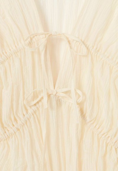 Tessuto color crema con due fiocchi legati e texture arricciata e raccolta.
