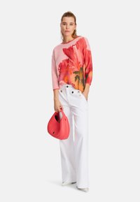 Knit sweater in pink with floral design, paired with white wide-leg trousers featuring button accents, and a textured red handbag.