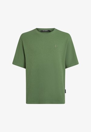 Zelena rebrasta majica s kratkimi rokavi in okroglim izrezom. Na prsih je subtilen izvezen logotip »KL«, ob strani pa etiketa.