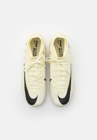 Botas de fútbol Nike en amarillo y blanco presentan una parte superior texturizada con rayas diagonales, el logo Swoosh en negro y cordones blancos.