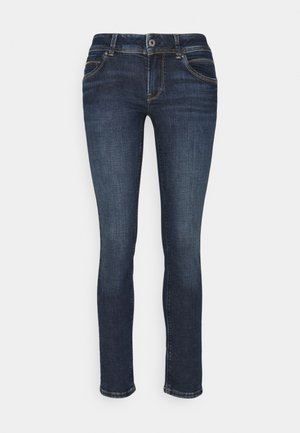 Tummansiniset slim fit -farkut, joissa etukappaleen nappi- ja vetoketjusuljin, etutaskut ja kontrastipistot valkoisella taustalla.