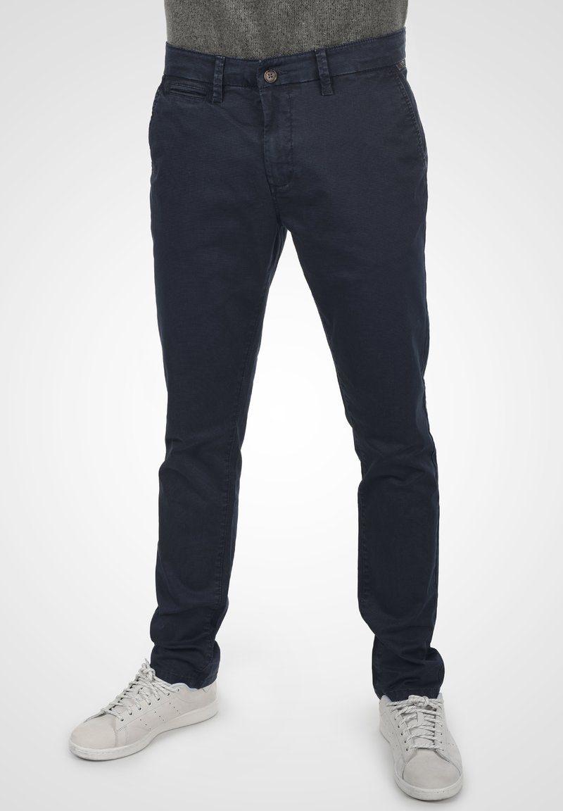 Mörkblå bomullschinos med slim fit, med knappstängning och sidofickor, i kombination med ljusgrå sneakers.