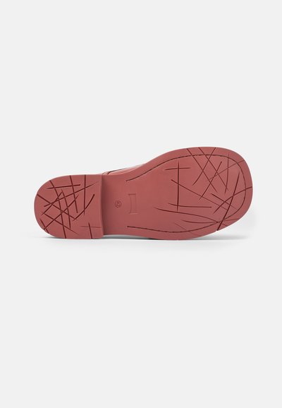 Red rubber shoe sole with a textured surface. Features a patterned tread for traction and a smooth, rounded toe area.
