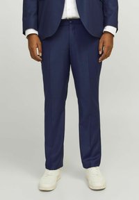 Pantalon de costume bleu marine ajusté avec une finition texturée, doté d'une taille à fermeture à bouton et de jambes droites. Associé à des baskets blanches.