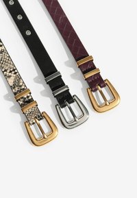 Három öv: egy kígyóbőr mintás arany csattal, egy fekete texturált öv ezüst csattal, és egy bordó szőtt öv arany részletekkel.