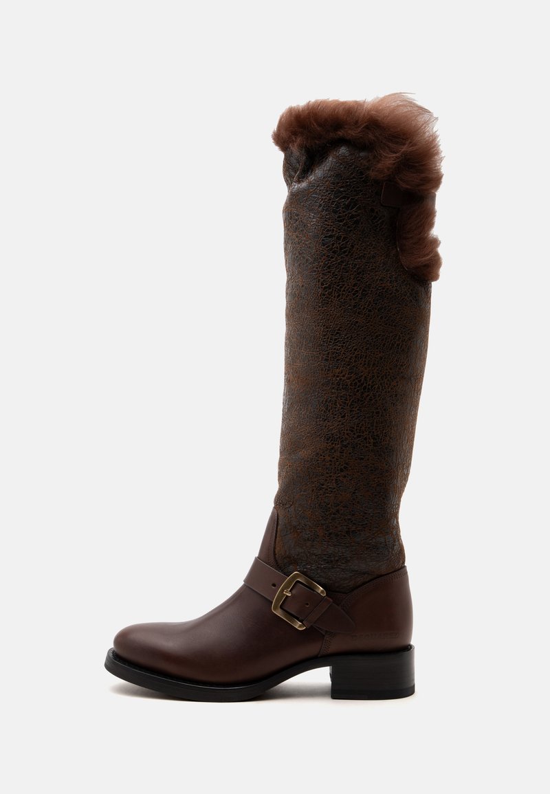 Botte haute en cuir marron avec une boucle latérale, tige supérieure texturée et une bordure en fourrure duveteuse autour du bord supérieur.