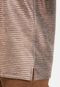 Top en tricot métallique dans des nuances de bronze et de beige avec un motif texturé en relief ; présente des fentes latérales et un design lisse et léger.