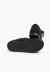 Scarpe nere in suede con suola in gomma piatta. Presentano una punta arrotondata e un dettaglio con fibbia laterale. La parte inferiore ha una texture antiscivolo per una migliore aderenza.