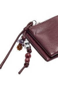 Portfel z bordowej skóry o teksturowanej powierzchni; posiada ozdobne koraliki i zawieszki na plecionym pasku; kompaktowy, prostokątny kształt.