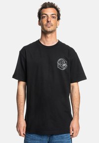 Black cotton t-shirt with a relaxed fit, featuring a white graphic print on the left chest. Short sleeves and crew neck design.