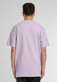 Lilac cotton t-shirt with a relaxed fit, short sleeves, and a round neckline. Smooth texture without visible graphics or patterns.