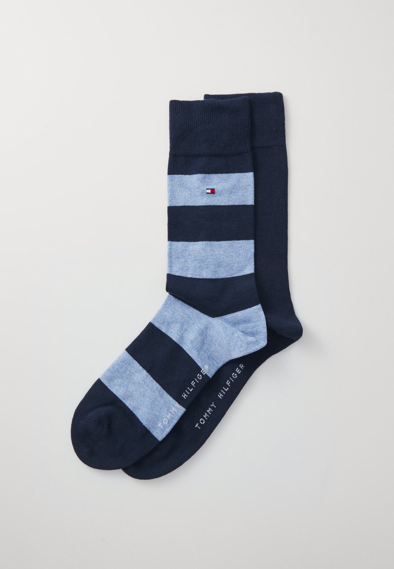 Meias de algodão com listras horizontais em azul marinho escuro e azul claro. Apresenta um pequeno logo e um punho canelado na parte superior. Textura suave.